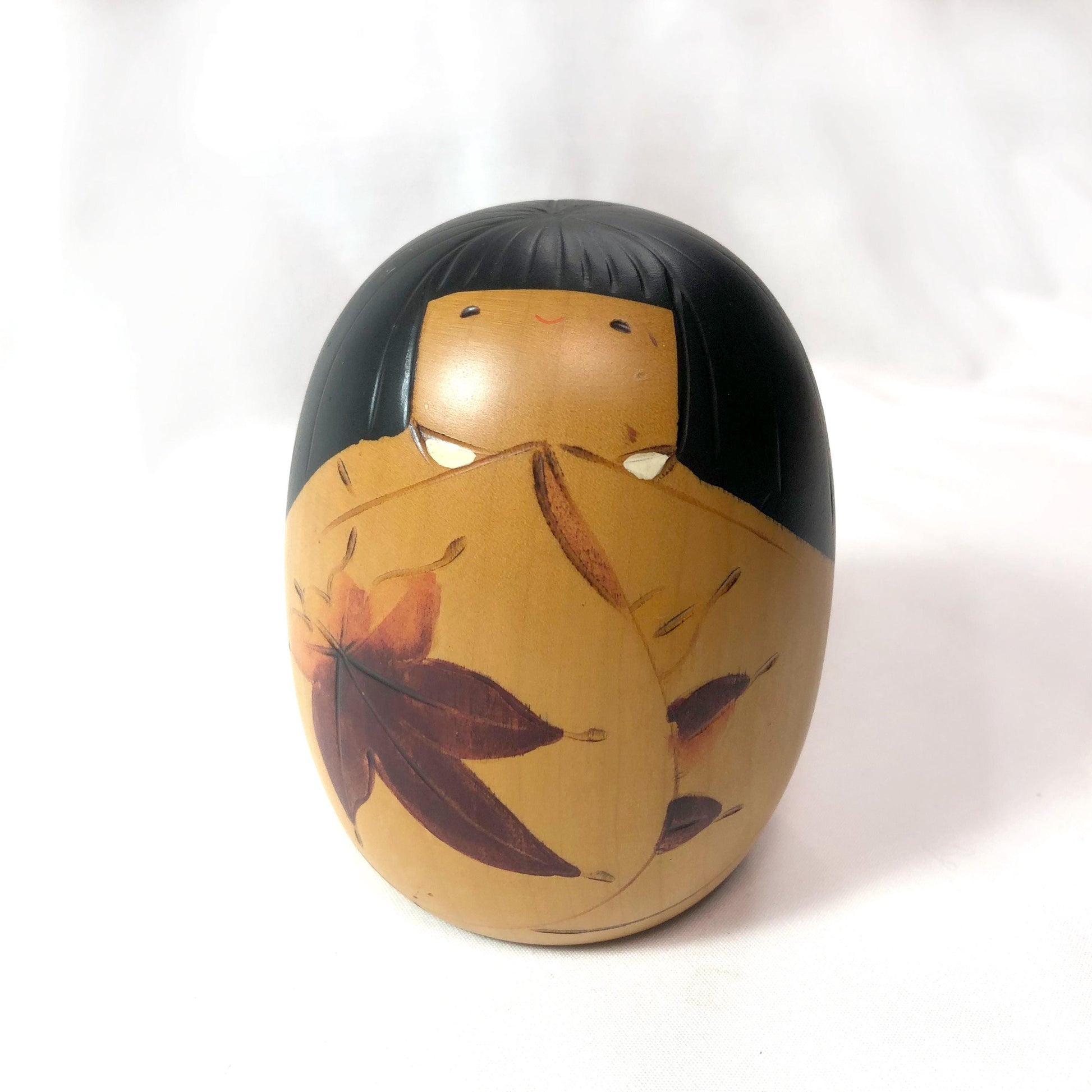 Cute wooden kokeshi doll with momiji leaf pattern by Usaburo