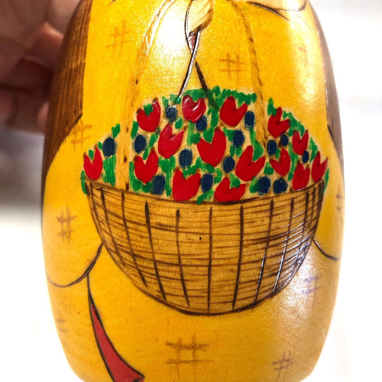Joyful wooden kokeshi doll with a basket of flowers