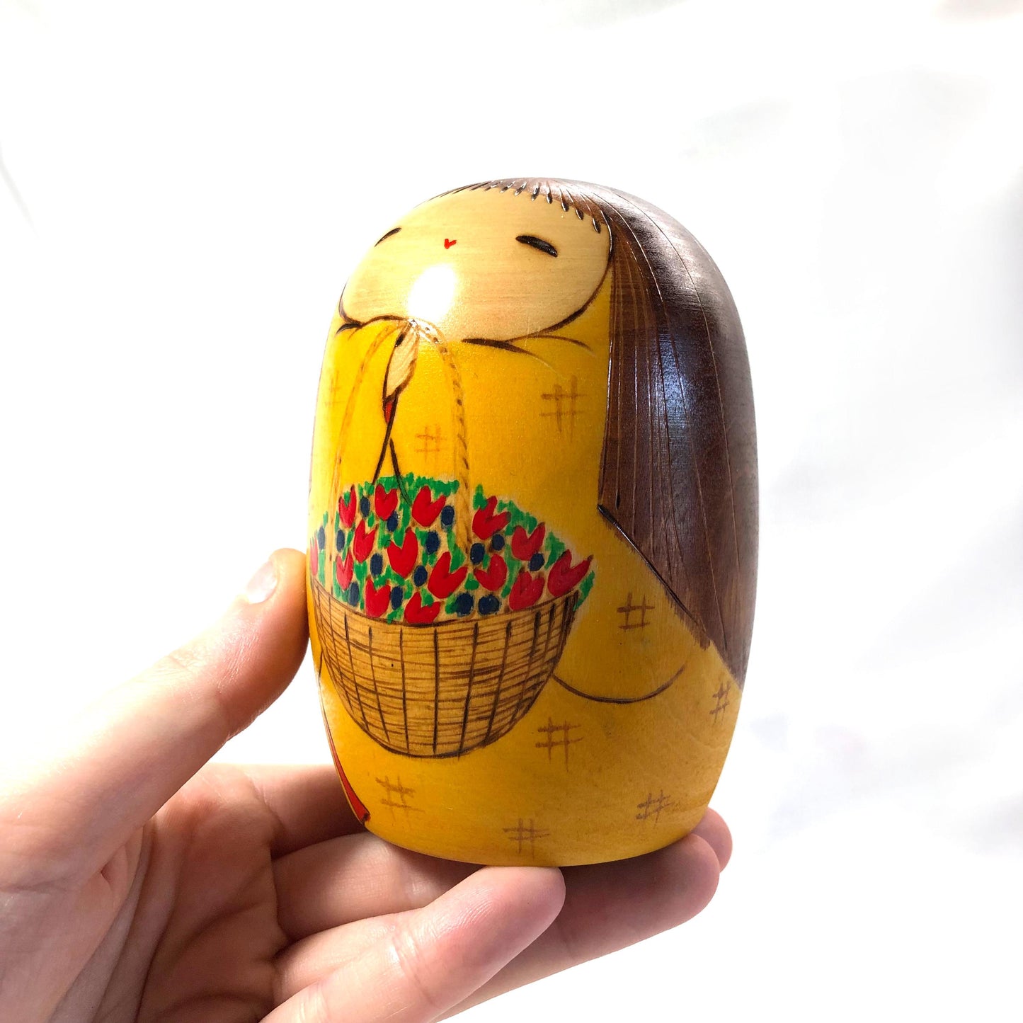 Joyful wooden kokeshi doll with a basket of flowers