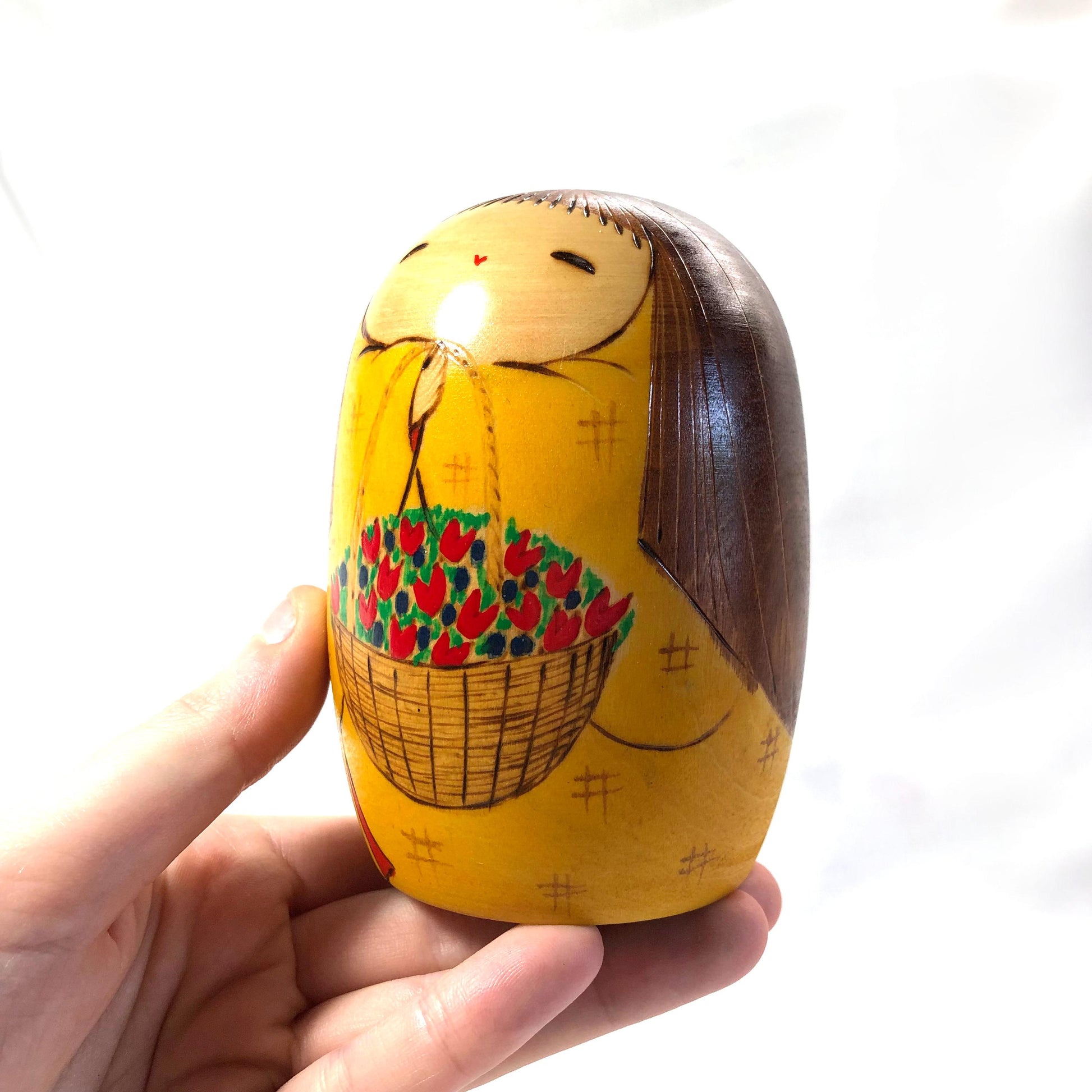 Joyful wooden kokeshi doll with a basket of flowers