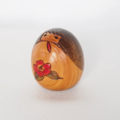 Miniature wooden kokeshi doll with a camellia flower