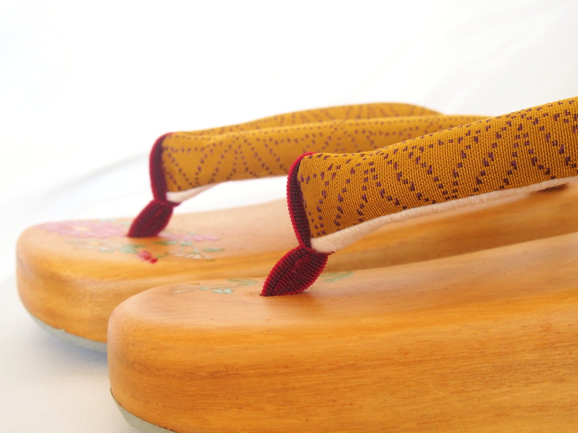 Elegant wooden geta- ocher and red traditional Japanese shoes with floral pattern