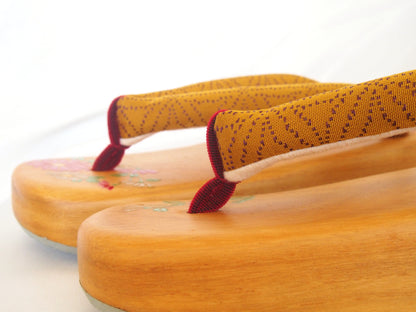 Elegant wooden geta- ocher and red traditional Japanese shoes with floral pattern