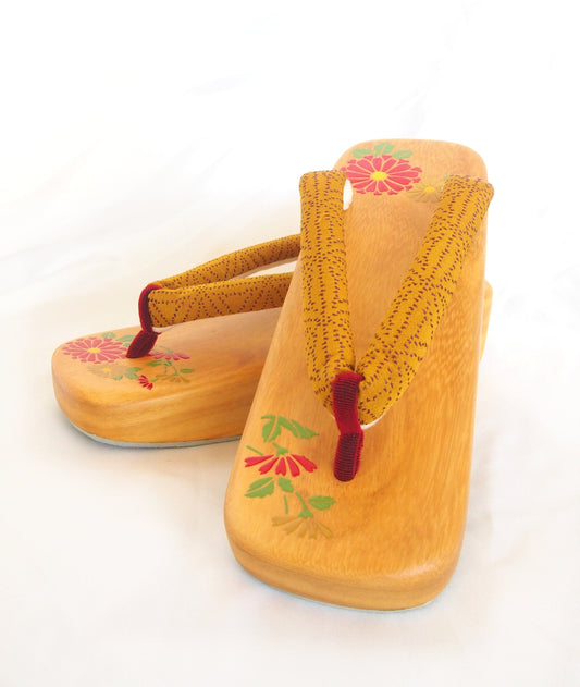 Elegant wooden geta- ocher and red traditional Japanese shoes with floral pattern